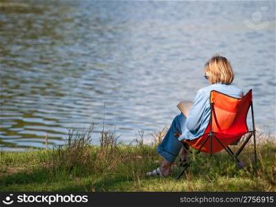 The woman reading the book on coast of lake