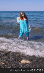 The woman, representing water, dressed in blue, standing on the shoreof lake Ontario in bright sunshine and the waves coming to shore.