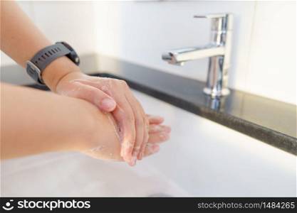The woman&rsquo;s hand is going to open the faucet to wash hands. To maintain cleanliness after entering the bathroom, the concept of health and cleanliness.