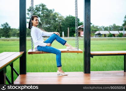 The woman sat on the swing and laid her hands on her knees