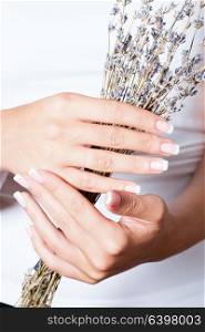 The woman shows a beautiful French manicure holds dry lavender. Unsurpassed French manicure