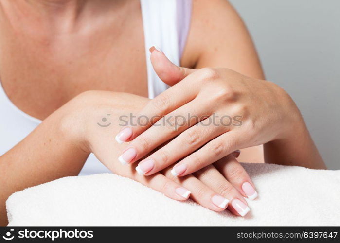 The woman shows a beautiful French manicure putting hand on one another. Unsurpassed French manicure