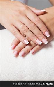 The woman shows a beautiful French manicure putting hand on one another. Unsurpassed French manicure