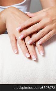 The woman shows a beautiful French manicure putting hand on one another. Unsurpassed French manicure