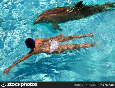 The woman swims in the sea near a dolphin