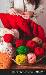 The woman that hold needles and knitting a red warm jacket on the market. Female knits sweater