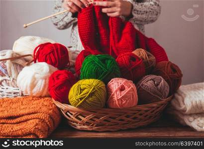 The woman that hold needles and knitting a red warm jacket on the market. Female knits sweater