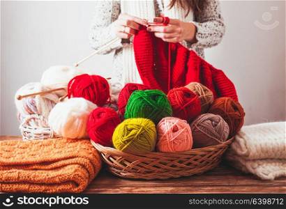 The woman that hold needles and knitting a red warm jacket on the market. Hobby concept of knit. Female knits sweater
