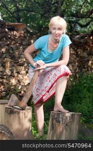 The woman with a splitting axe prepares firewood to heat the house