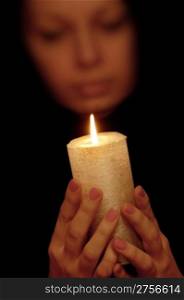 The woman with burning candle. Selective focus on a candle
