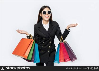 The woman wore black clothes and glasses, along with many bags, to go shopping.