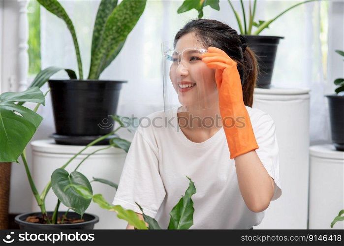The woman wore orange gloves and planted trees in the house.