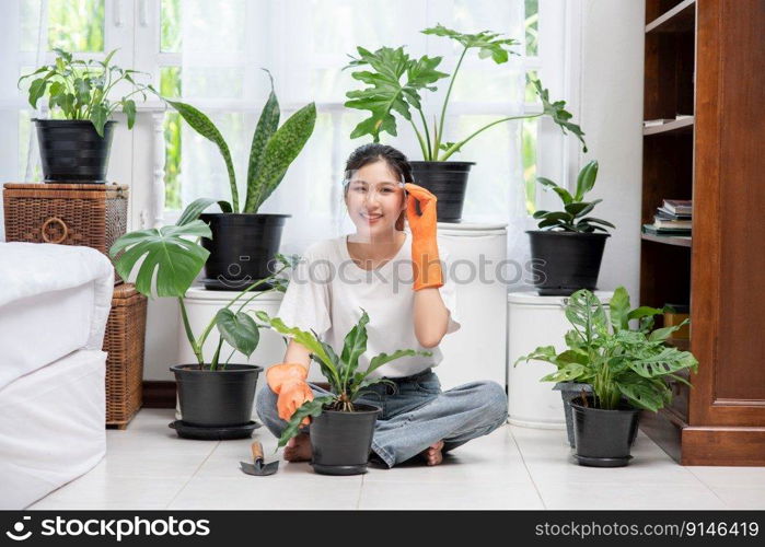 The woman wore orange gloves and planted trees in the house.