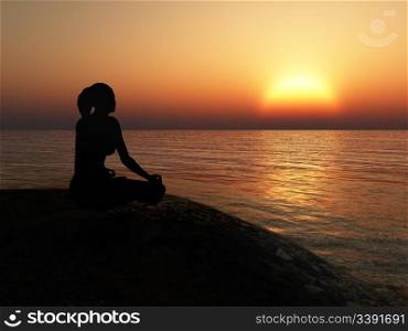 The women in a pose of a lotus. A sunset above ocean