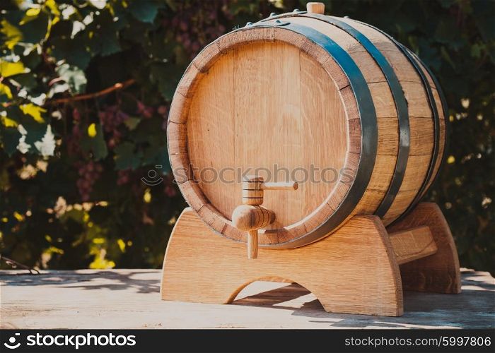 The wooden barrel with wine on a table outdoor. Winery culture. The wooden barrel