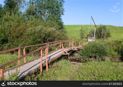 The wooden bridge through a stream to a well