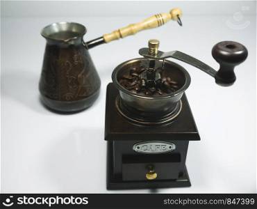 The wooden coffee grinder with coffee beans and cezva on white background