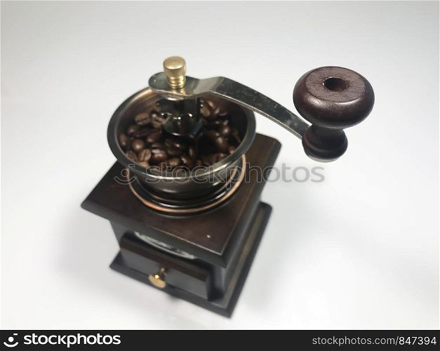 The wooden coffee grinder with coffee beans on white background