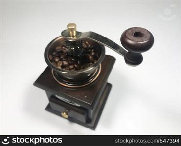 The wooden coffee grinder with coffee beans on white background
