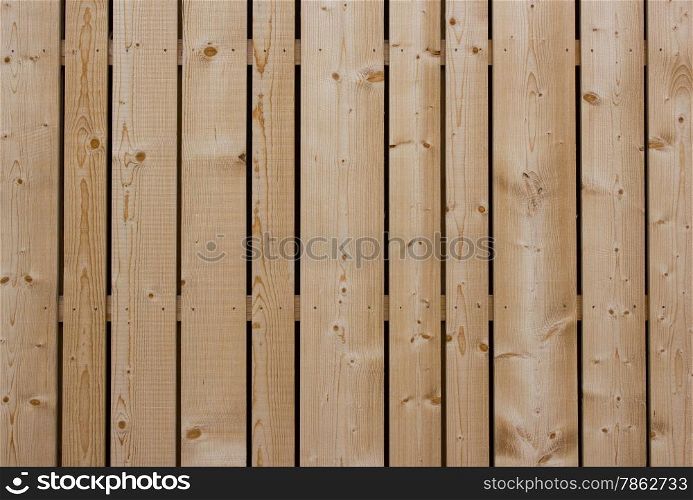 The wooden fence with a symmetrical rhythm of wooden planks