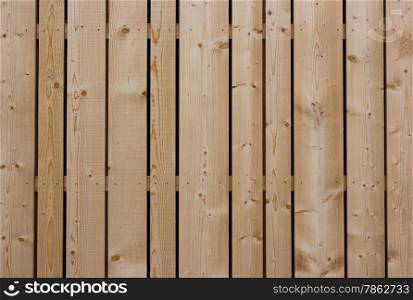 The wooden fence with a symmetrical rhythm of wooden planks