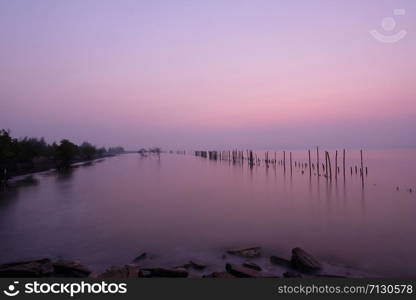 The wooden poles were lined up in a row in the sea. Appears as a reflection on the water surface During the sunrise on a new morning.