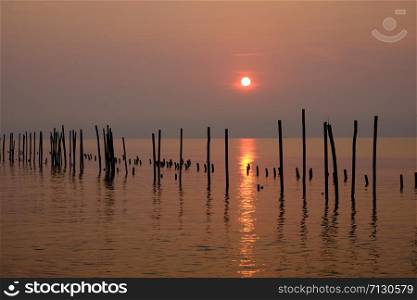 The wooden poles were lined up in a row in the sea. Appears as a reflection on the water surface During the sunrise on a new morning.