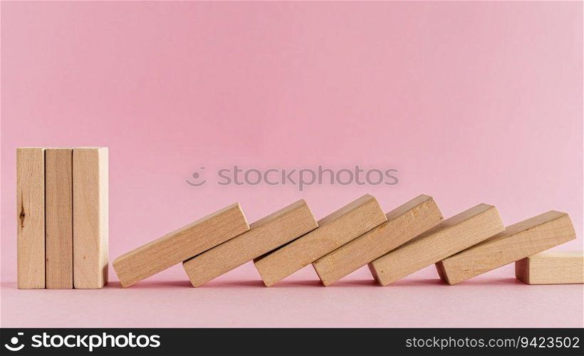 The wooden toys arranged in a horizontal row but the next others falling down on pink background for leisure activities concept