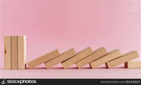 The wooden toys arranged in a horizontal row but the next others falling down on pink background for leisure activities concept