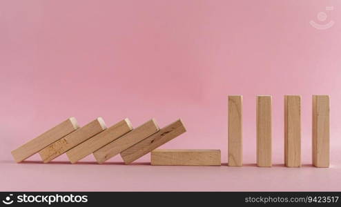 The wooden toys falling down but the next others that is far away could stand on pink background for social distancing concept