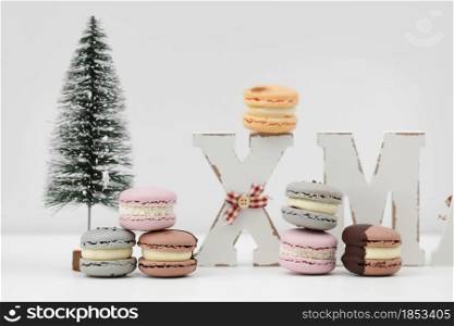 The wooden word xmas with colorful macaroons or macarons and christmas tree on white background. Xmas decoration. New Year home decor.. The wooden word xmas with colorful macaroons or macarons and christmas tree on white background. Xmas decoration. New Year home decor