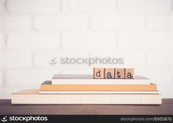 The word Data, alphabet on wooden cubes on top of books. Background copy space, vintage and minimal style. Research study or information analysis, facts and knowledge for education or business.