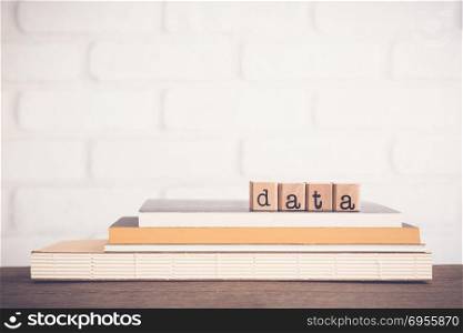 The word Data, alphabet on wooden cubes on top of books. Background copy space, vintage and minimal style. Research study or information analysis, facts and knowledge for education or business.