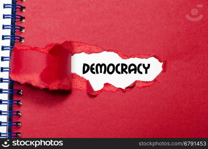 The word democracy appearing behind torn paper