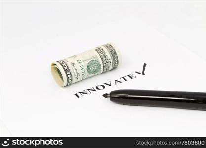 The word, innovate, is printed out with a black check next to it and rolled US currency above. Black felt tip pen is on the right;