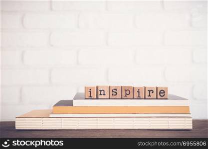 The word Inspire, alphabet on wooden cubes on top of books. Background copy space, vintage and minimal style. Concepts and ideas for creativity in new production or invention works.