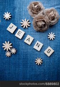 "The word "Jeans" spelled out with wooden letter tiles on denim fabric"
