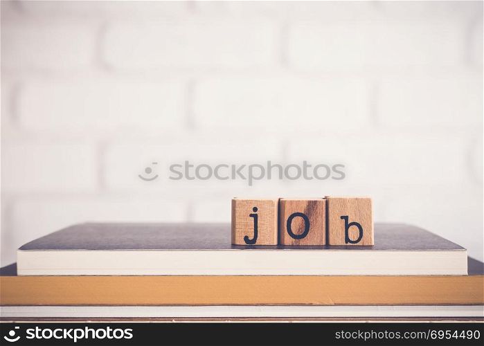 The word Job, alphabet on wooden cubes on top of books. Background copy space, minimal. Job application process, creating safe job procedures and work practices for employee and human resources.