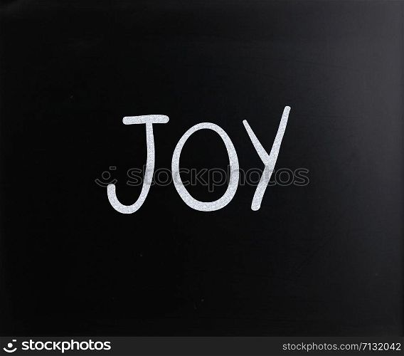 "The word "Joy" handwritten with white chalk on a blackboard"