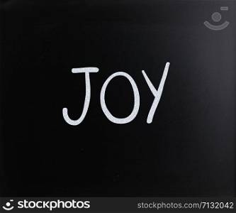 "The word "Joy" handwritten with white chalk on a blackboard"