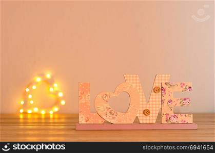 The word love in pink with an out of focus light heart shape