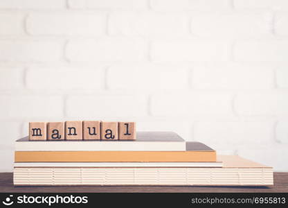 The word Manual, text on wooden cubes on top of books. Background copy space, vintage minimal style. Concepts of help information, Instructions or user guide for education and business products.