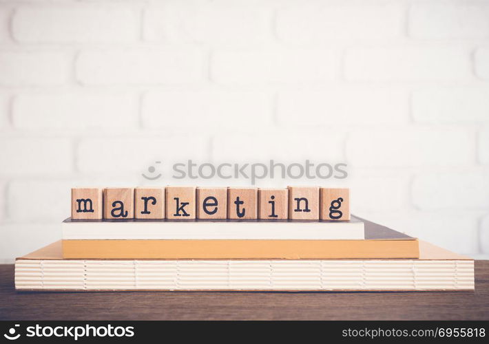 The word Marketing, text on wooden cubes on top books. Background copy space, vintage minimal style. Business management, education, research and innovation for keep satisfy customer relationships.