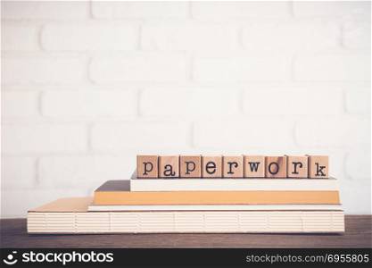 The word Paperwork, alphabet on wooden cubes on top of books. Background copy space, vintage and minimal style. Concepts of information or written documents for education or business work.