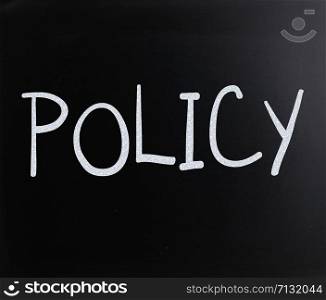 "The word "Policy" handwritten with white chalk on a blackboard"