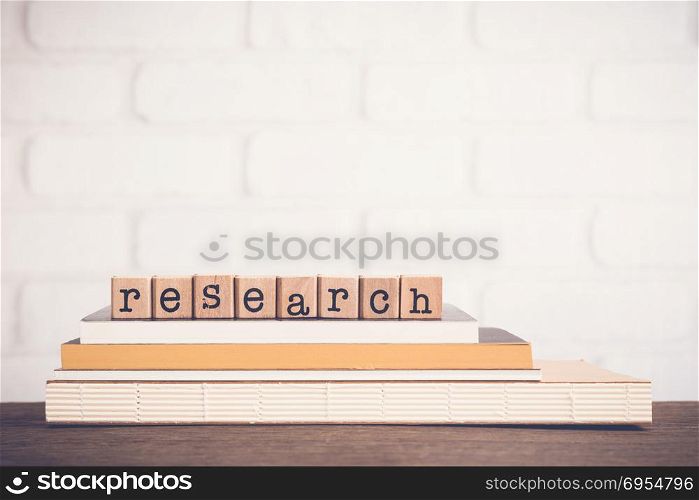 The word Research, alphabet on wooden cubes on top of books. Background copy space, minimal. Concept to create or manage project study and knowledge systematic work for education, business marketing.