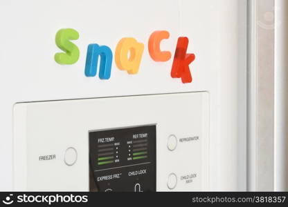 The word &rsquo;Snack&rsquo; spelled out in fridge magnets on the door of a fridge.