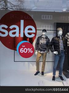the word sale in shop window of clothing store and male mannequins