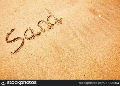 The word sand written in the sand at a beach - background texture