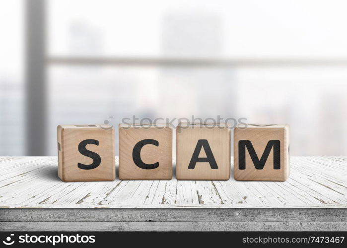 The word scam made of wooden blocks on a table in a bright office room